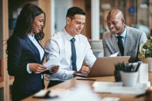 Three business professionals in suits and ties collaborating over a laptop, engaged in a discussion or presentation.