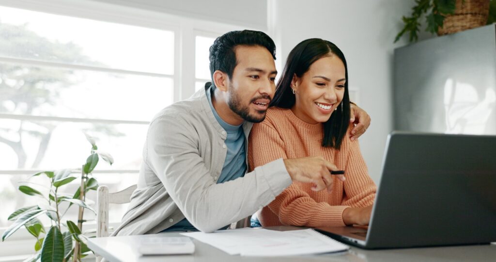 Kitchen, couple and smile with laptop for finance, track expenses and success for budget goals. Discussion, man and woman with tax review for checking, handle savings and mortgage document at home.